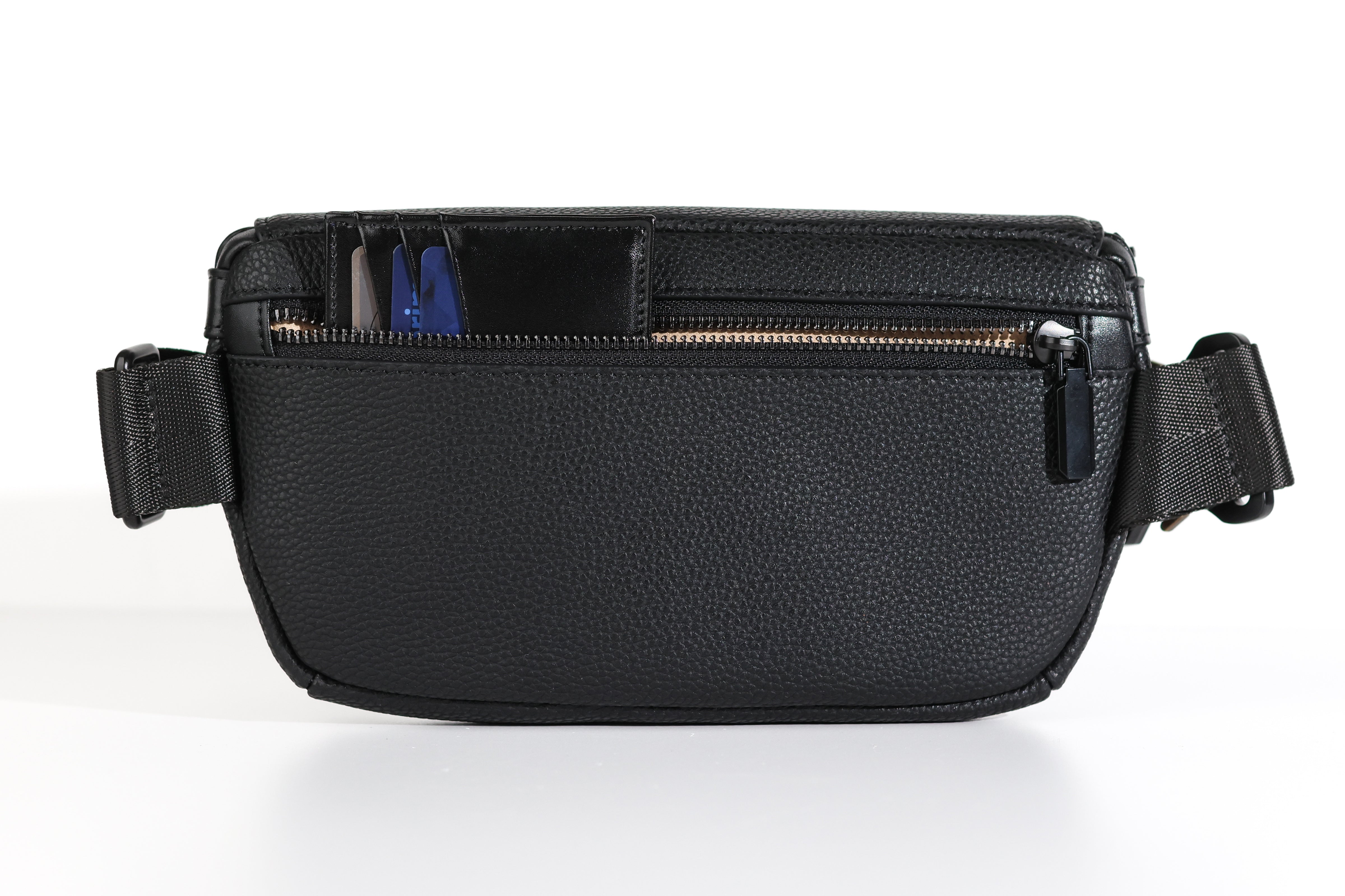The rear of a black leather sling bag/black leather belt bag/black leather crossbody bag/black leather waist bag/black leather travel pouch with an open zipper that has a black wallet with credit cards sticking out of it.