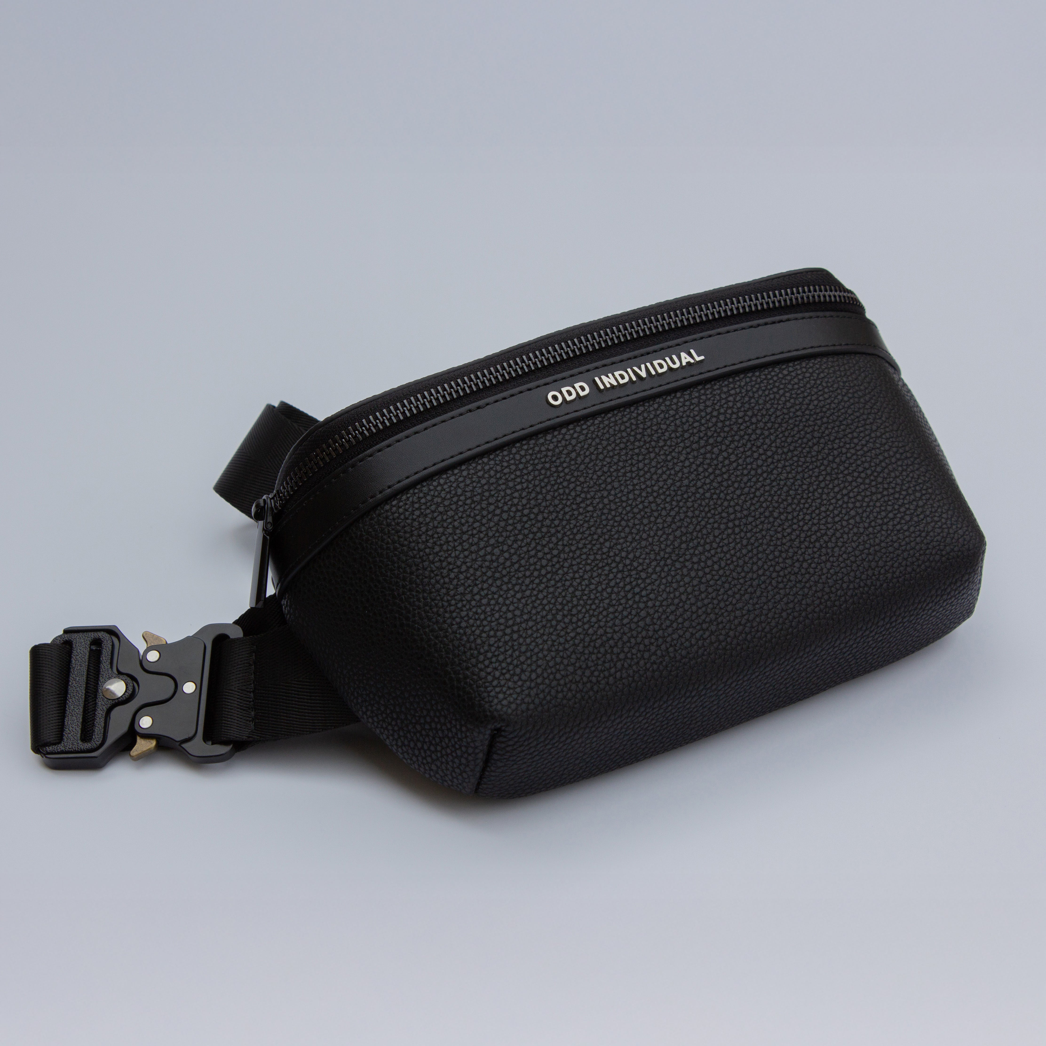 Men's sling bag with black pebble leather with 'Odd Individual' branding on a light gray background
