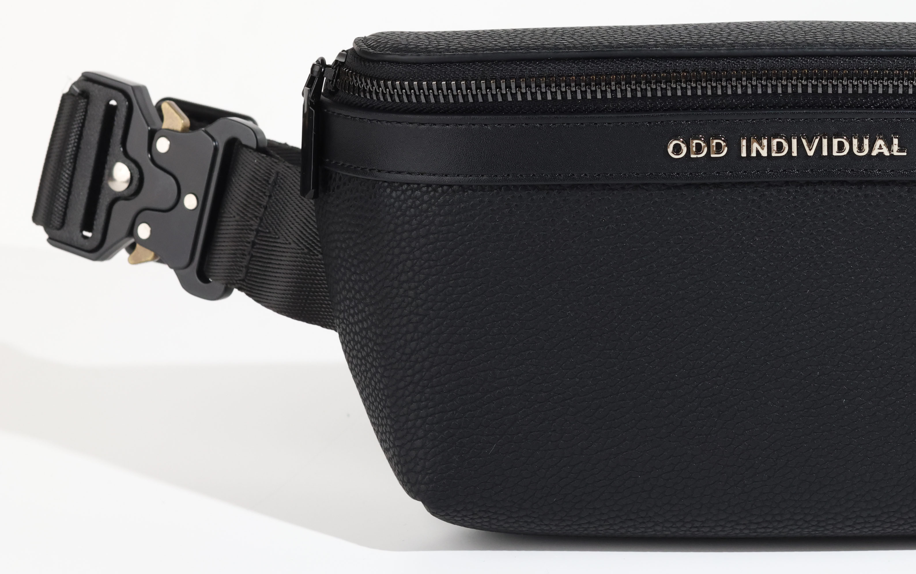 Black leather sling bag/black leather belt bag/black leather crossbody bag/black leather waist bag/black leather travel pouch with angled strap with brand name 'ODD INDIVIDUAL'  on a white background